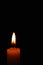 Candle flame on black background. Single lit candle with quite flame. Dramatic burning candle flame on a black background with