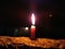 A CANDLE FLAME GIVE LIGHT IN DARK NIGHT WITH LIGHTING BEHIND