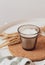 A candle in a glass beaker on a cotton napkin on a white table, next to it is a bouquet of dried flowers. Warm colors