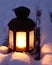 Candle lamp on snowy bench