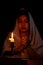 Candle light with blur young girl praying in dark night background. Woman person worship God with faith and belief. religion,