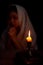 Candle light with blur young girl praying in dark night background. Woman person worship God with faith and belief. religion,