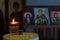 Candle light illuminating in front of orthodox saint pictures.