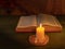 Candle lighting a bible on a wooden background. Concept of spirituality, enlightenment and wisdom