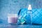 Candle perfume and cosmetic bag with water drops in shallow depth of field on blue background