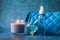 Candle perfume and cosmetic bag with water drops in shallow depth of field on blue background