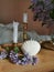 Candle in shell form, candels in vintage brass candlesticks and purple lilac flowers on the wooden tabletop.