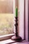 Candle in vintage copper candle holder on wooden table near the window in rural house interior