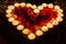 Candlelights shine in form of the heart with red roses petals
