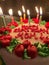 Candlelit Birthday Cake with Red and Green Decorations