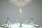 A candlelit dinner setting with an elegant crystal chandelier hanging above a round table.