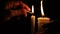 Candlelit Reverie: Hand Igniting White Candle in Enigmatic Darkness