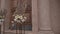 Candles in candlesticks stand next to bouquets of flowers on stands in front of the door of the church