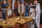 Candles in a golden chandelier in the Orthodox Church, close-up, priest with parishioners in the background out of focus