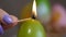 Candles made in shape of easter egg. Green candles. Female hand lights candles.