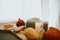 Candles, pumpkins, autumn leaves, chestnuts and corn on wooden window sill in rustic room. Cozy seasonal home decor. Rural