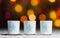 Candles standing in snow with defocussed fairy lights, orange or golden bokeh in the background