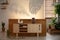 Candles on wooden cupboard in bedroom interior with plants and shadows on the wall. Real photo