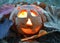 Candlestick pumpkin with a burning candle inside, among fallen leaves, symbol of Halloween