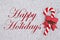 Candy cane on plush gray material with text Happy Holidays