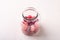 Candy canes sweets in form of juicy berries in glass jar on white wooden background