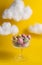Candy sea stones in a glass on a yellow background with clouds close up