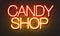 Candy shop neon sign on brick wall background.