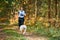 Canicross cross country running with dog, female musher running with Samoyed dog, sled dog racing