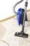 Canister modern vacuum cleaner blue for cleaning the house on the background of a soft beige carpet.