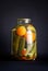 Canned cucumbers and tomatoes in a large three-liter jar on a black background. The concept of homemade products