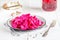 Canned fermented purple cabbage with beets, carrots and garlic on a white plate,on a white napkin,on a light natural background,