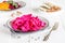 Canned fermented purple cabbage with beets, carrots and garlic on a white plate,on a white napkin,on a light natural table, in a