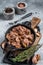 Canned stewed horse and beef meat in a pan. Gray background. Top view