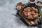 Canned stewed horse and beef meat in a pan. Gray background. Top view. Copy space