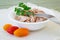 Canned tuna fillet in white porcelain bowl, fork, parsley and three cherry tomatoes on a beige table table napkin. Seafood,