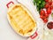 Cannelloni with filling of ricotta and parsley, baked with bÃ©chamel sauce, top view, white marble background