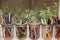 Canning jars filled with crayons, pastels and markers sitting on an open windowsill with flowers outside seen through a window scr