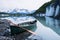 Canoe resting on rock covered ice of Valdez Glacier with icebergs behind. Valdez, Alaska