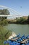 Canoes anchored at harbour in green river with the bridge in the background. Maremma, Tuscany, Italy