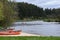 Canoes docked on the shore of a river, with a lush trees in the background