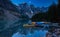 Canoes on a jetty at Moraine lake, Banff national park in the Rocky Mountains at night with moon, Alberta, Canada