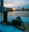 Canon RP camera and coffee thermos lies on Grunwaldzki bridge at cloudy sunset over Odra river