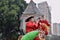 CANTON, CHINA â€“ CIRCA DECEMBER 2017: Street vendor in Guangzhou dresses up as a colorful rooster who blows into a horn.