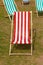 Canvas deckchairs on a grassy lawn in the summer.