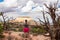 Canyonlands - Woman next to old dry juniper tree with scenic view of sandstone summit Aztec Butte, Utah, USA