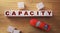 Capacity word made of wooden cubes on a wooden background with red toy car. Business capacity logistic management concept