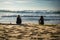 Capbreton, France - October 4, 2017: back view of women girls surfers sitting on sandy beach on surfboard