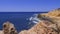 Cape near the sea with blue water waves, rocks and sky, slow motion