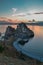 Cape Shamanka rock in clear blue Lake Baikal among rocks, coast, colorful pink sunset