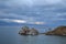 Cape Shamanka rock in clear Lake Baikal among mountains and clouds